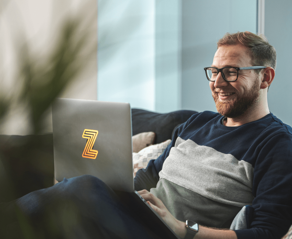 30 year old male customer experience expert sitting on his sofa at home and smiling